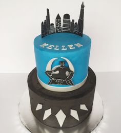 a blue and black cake sitting on top of a white tablecloth covered plate with city skylines in the background