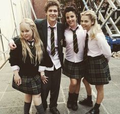 four young people dressed in school uniforms posing for the camera