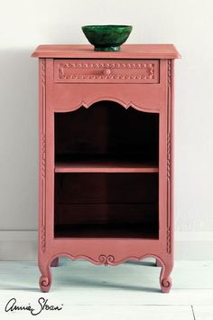 a small pink cabinet with a green bowl on it's top and bottom shelf