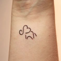 a small tattoo on the wrist of a woman with an elephant and heart in it