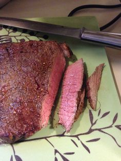 a piece of steak on a cutting board next to a knife