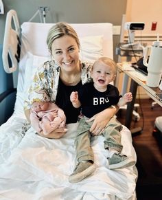 a woman sitting next to a baby in a hospital bed with her arm around the baby's leg