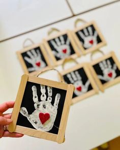 a person holding up a handprinted picture with red heart on it and six other pictures in the background