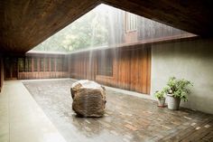 a large rock sitting on top of a wooden floor next to a stone covered wall