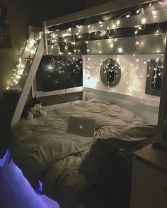 a bed room with a laptop on top of it next to a ladder that is lit up