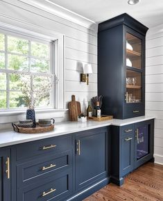 a kitchen with dark blue cabinets and white counter tops, gold trimming on the doors