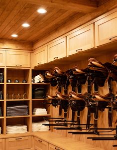 a room with lots of wooden cabinets and many different types of shoes hanging on the wall