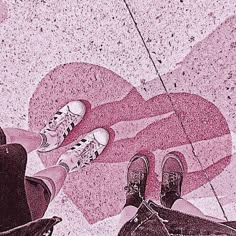 two people standing next to each other in front of a heart shaped floor with their feet on the ground