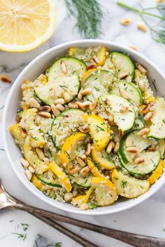 a white bowl filled with cucumbers, squash and pine nuts on top of a marble table