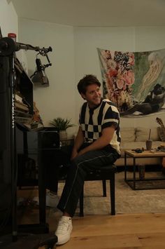 a man sitting on a chair in front of a piano and looking at the camera