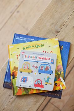 two children's books sitting on top of a wooden floor next to each other