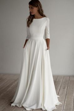 a woman in a long white dress standing on a wooden floor with her back to the camera