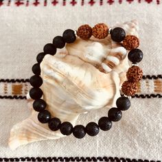 The Rudram Wrist Mala was designed to reflect earth colors . The combination of Lava Rocks, Rudraksha seeds and tiny silver Hematite beads are a winning of choice of earth colors and grounding energy. - Lava Rock is known to be a grounding stone that strengthens one's connection to Mother Earth. It activates courage and provides stability through times of change. - Rudraksha is the seed of a broad-leafed evergreen tree found mainly in the Himalayan foothills. It is believed that wearing these be Adjustable Earthy Beaded Bracelets For Meditation, Hand-strung Brown Beaded Bracelets For Meditation, Spiritual Brown Beaded Bracelets, Brown Hand-strung Beaded Bracelets For Meditation, Spiritual Brown Bracelet For Meditation, Brown Gemstone Beads Bracelets For Meditation, Brown Spiritual Bracelets For Meditation, Hand Wrapped Brown Beaded Bracelets For Meditation, Spiritual Lava Stone Bracelets With 8mm Beads