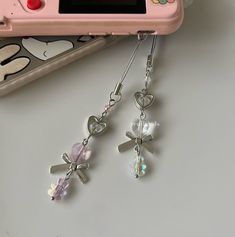 two charms are attached to a pink camera