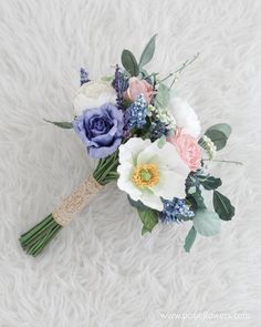 a bridal bouquet on a white furnishing with blue, pink and peach flowers