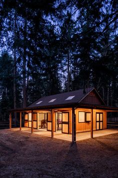 a small cabin is lit up at night in the woods