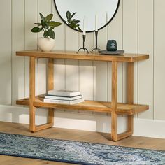 a wooden table with a mirror on top of it next to a rug and plant