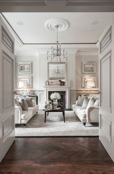 a living room filled with furniture and a chandelier hanging from the ceiling over a fire place