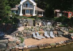 a house on the shore with lawn chairs