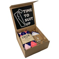 an open cardboard box with ties and other items in it that says time to suit up