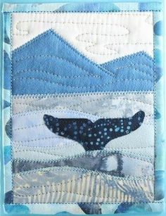 a blue and white quilted wall hanging with a whale on it's side