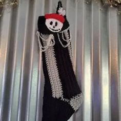 a black sock with a skull on it hanging from a metal wall in front of some tin foil