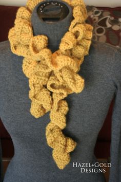 a woman wearing a yellow crocheted scarf on top of a mannequin