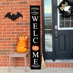 a welcome sign next to a brick wall with a broom and pumpkins on it