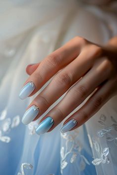 a woman's hand with blue and white manicures on her nails, wearing a wedding dress