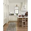 an open kitchen with white cabinets and wooden floors, along with a rug on the floor