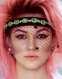 a woman with pink hair is wearing a veil and headpiece that has green beads on it