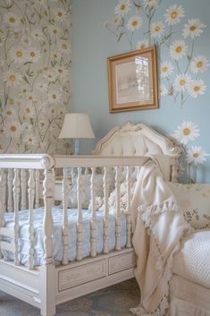 a white crib in a blue room with flowers on the wall and a lamp next to it