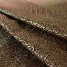 close up view of the texture of an alligator skin leather material that is brown and black