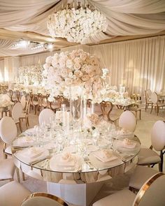 an elegant wedding reception with white flowers and crystal vases on the center table, surrounded by gold chairs