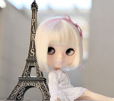 a doll sitting next to the eiffel tower