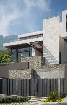 a modern house with stone walls and metal railings on the front yard, overlooking mountains