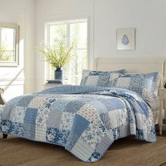 a blue and white quilted bed in a room with two chairs next to it