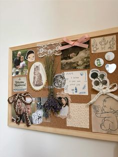 a cork board covered in pictures and magnets next to a vase with flowers on it