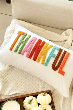 a pillow with the word thank written on it next to some pumpkins and candles