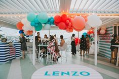 a group of people sitting at a table with balloons hanging from the ceiling above them