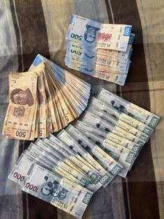 several stacks of mexican currency sitting on top of a plaid tablecloth with the tops folded down