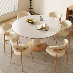 a white table with chairs around it and a book on the table next to it