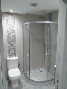 a white toilet sitting next to a shower in a bathroom under a skylight and tiled walls