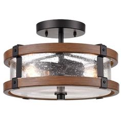 a semi - flush ceiling light with wood accents and clear glass in an industrial style