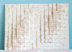 a wall made out of wood blocks on top of a white bedding with blue walls in the background