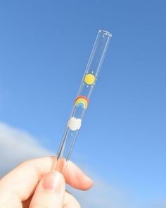 a person holding a tube with a rainbow on it in front of a blue sky