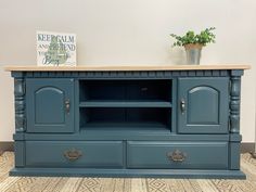 a blue entertainment center with two drawers and a potted plant on top