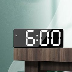 an alarm clock sitting on top of a wooden table in front of a green wall