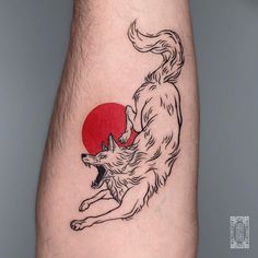 a tattoo on the leg of a man with a wolf and red sun behind it