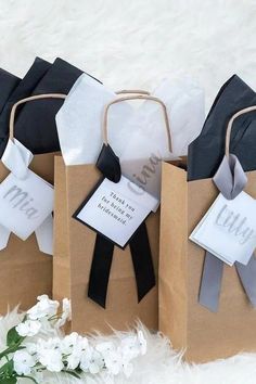 four brown paper bags with black and white ribbons